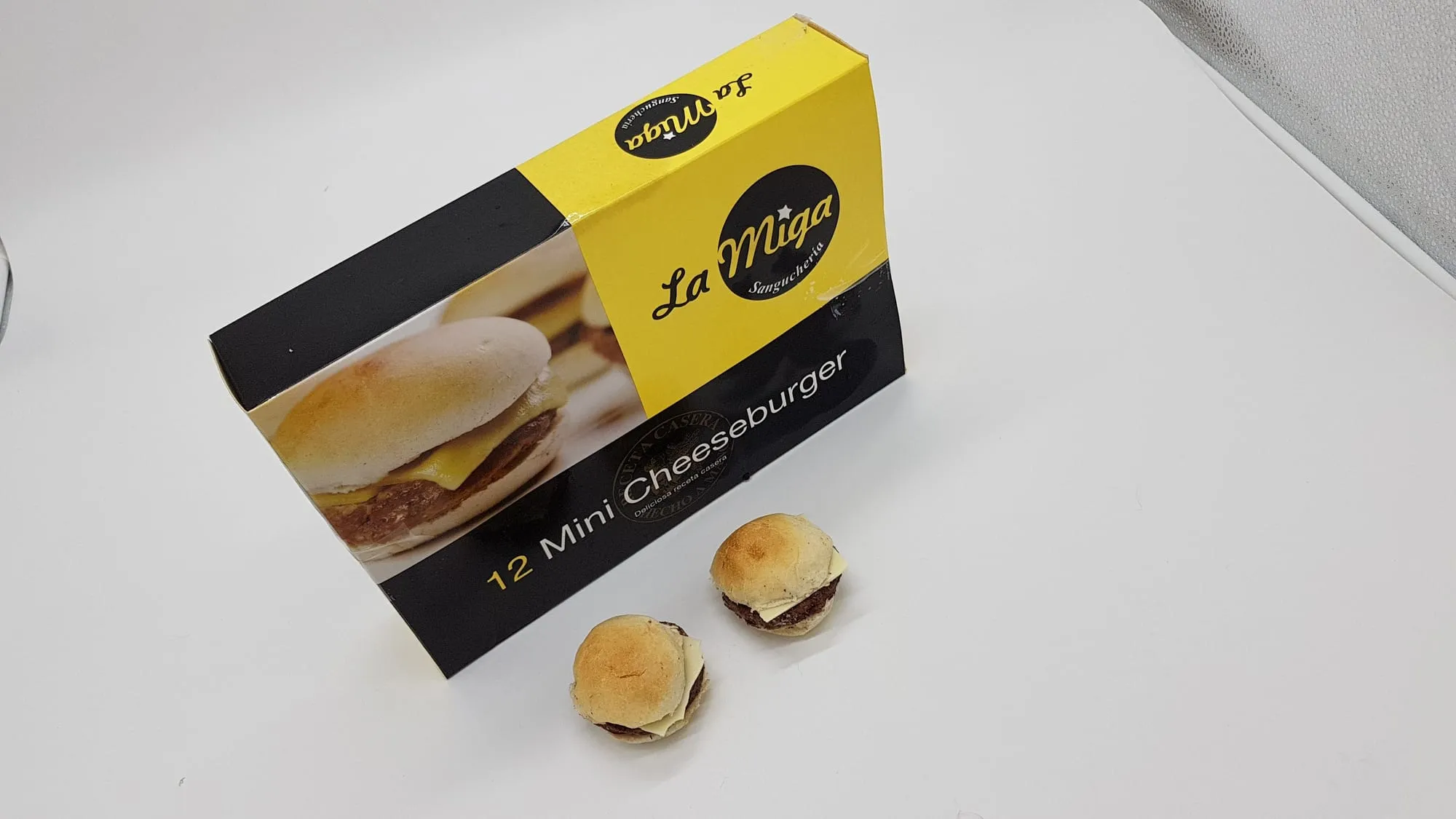 Caja de La Miga de doce mini cheeseburgers, con dos de las hamburguesas al lado
