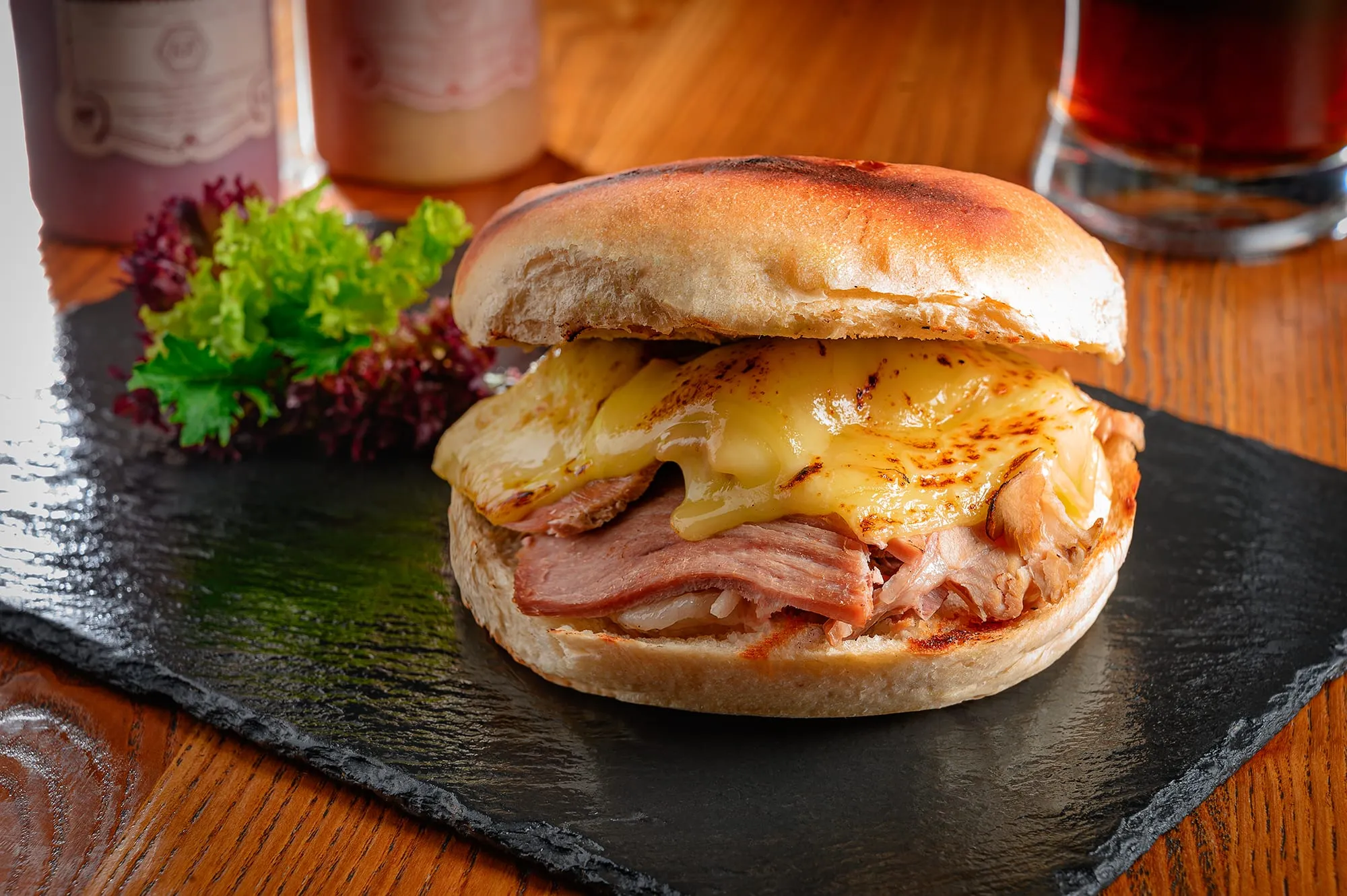 Sánguche de churrasco con jamón y queso fundido sobre una pizarra de piedra