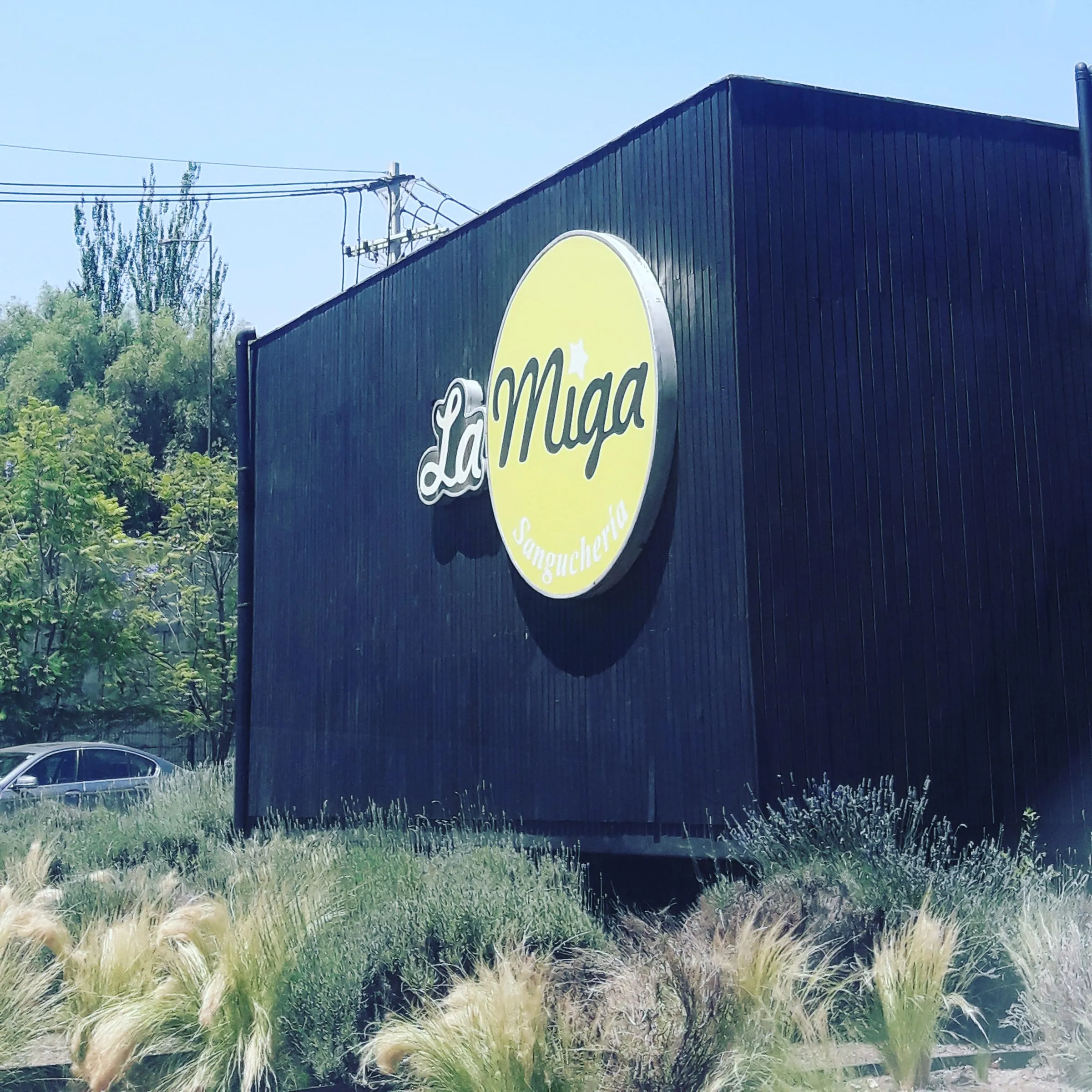 Fachada de La Miga, con el sello dorado del logo sobre el revestimiento negro del edificio