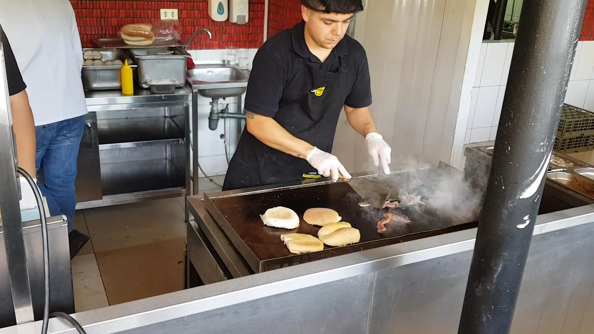 Cocinero de La Miga tostando panes y carne sobre la plancha caliente de la cocina