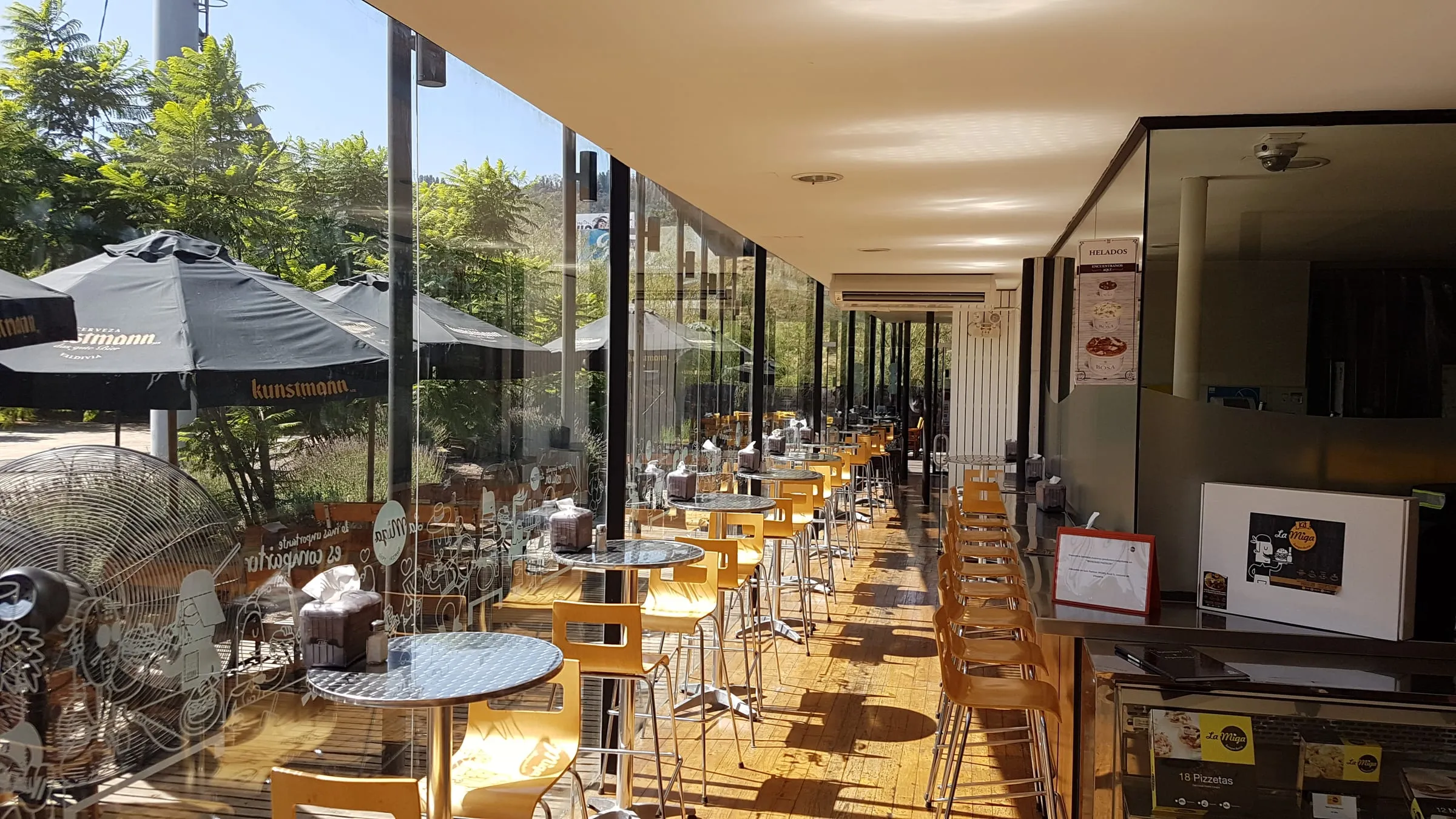 Comedor de La Miga, con las mesas corridas hacia la terraza y los quitasoles al fondo