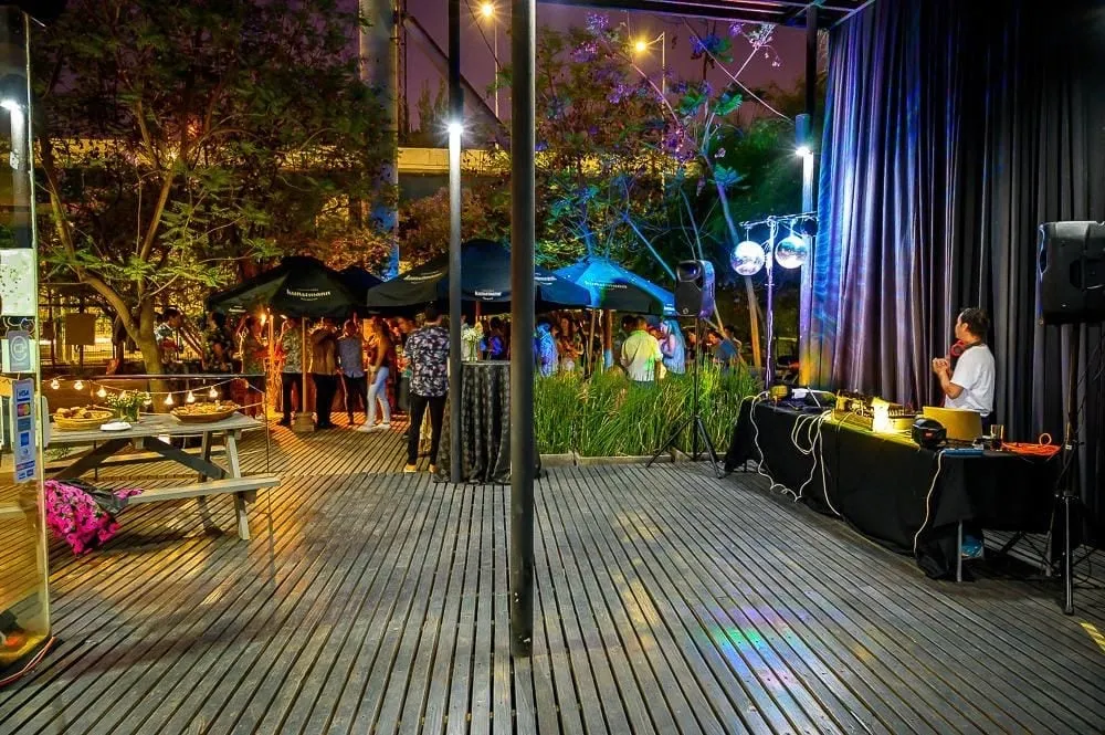 La terraza de La Miga de noche, con guirnaldas encendidas y los árboles iluminados de azul